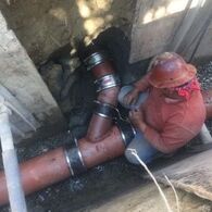 Construction worker sitting on underground pipeline