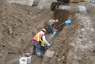 Two construction workers inside a dirt trench
