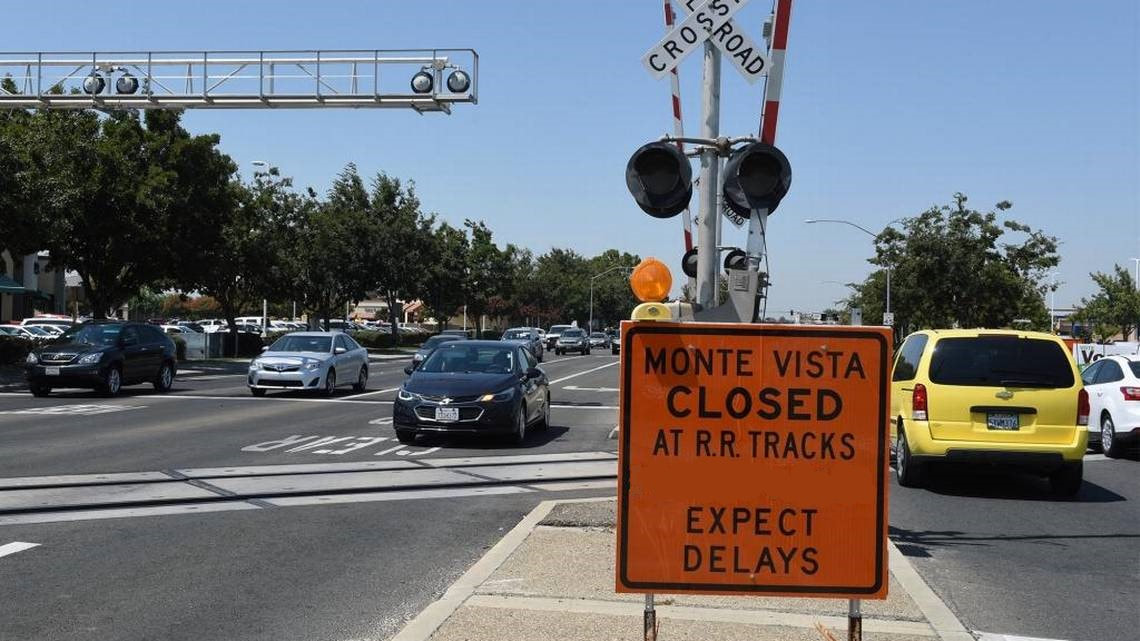 Streets by railroad tracks with orange construction sign reading Monte Vista Closed at RR Tracks Expect Delays