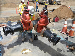 A large valve lifted off the ground with construction workers in the background